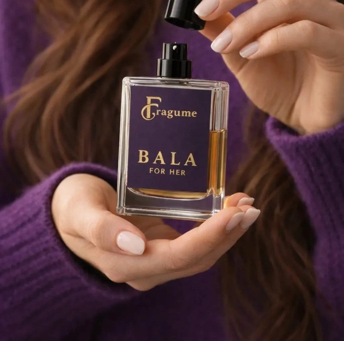 Fragume Bala Eau De Parfum for her in a sleek glass bottle with a purple label and gold text held by a woman.