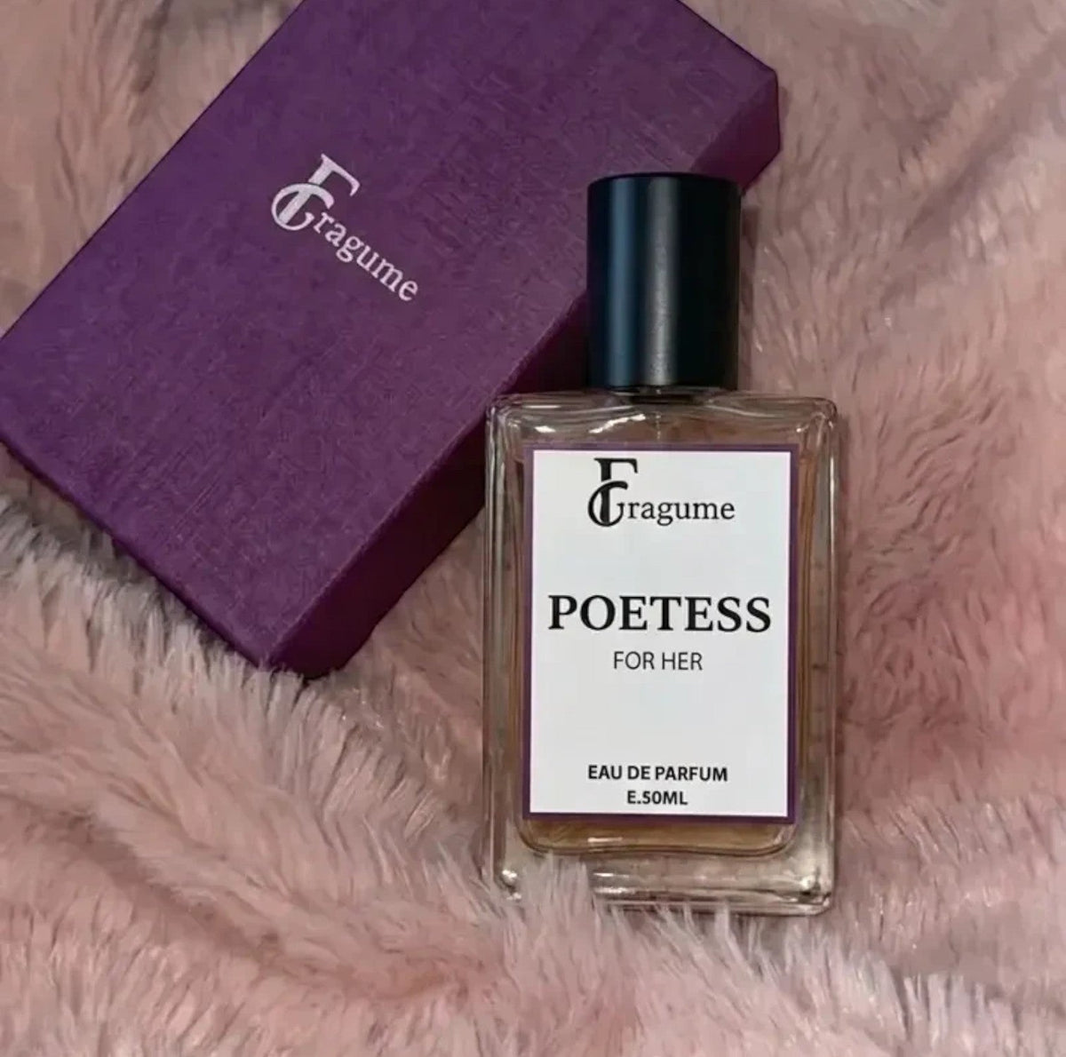 fragume Poetess Eau De Parfum in a glass bottle next to a textured purple gift box on a soft pink faux fur surface.