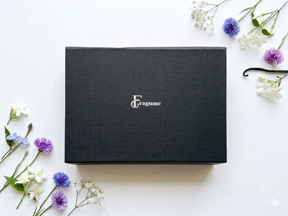 fragume 4 pocket perfume set in a sleek black gift box surrounded by delicate purple and white flowers
