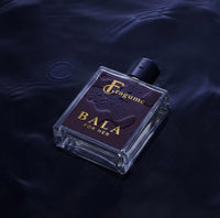 Fragume Bala Eau De Parfum in a sleek purple glass bottle with gold lettering, resting in dark rippling water.