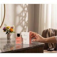 fragume Bloom Spirit Eau De Parfum bottle and box on a marble vanity with a floral bouquet in the background