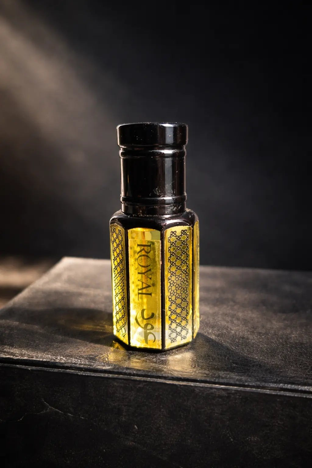 fragume Royal Oud Attar concentrated perfume oil in an elegant hexagonal glass bottle with intricate gold detailing.